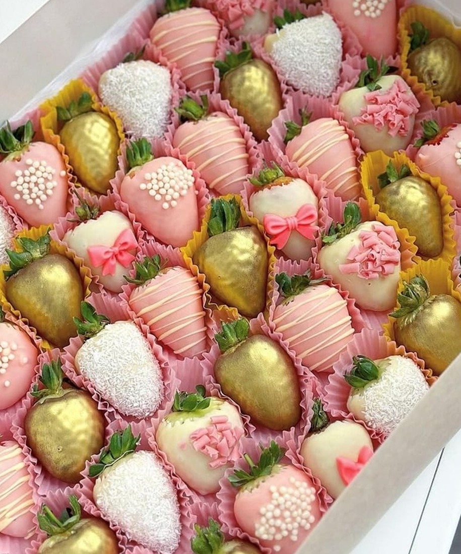 Tierna caja de fresas con chocolate dorado, rosa y blanco.